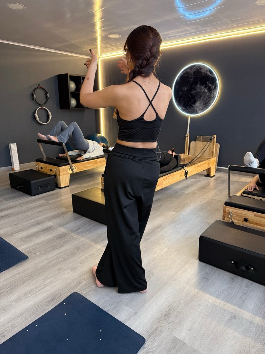Coach de pilates corrigiendo a sus alumnos en el Reformer, en un grupo pequeño