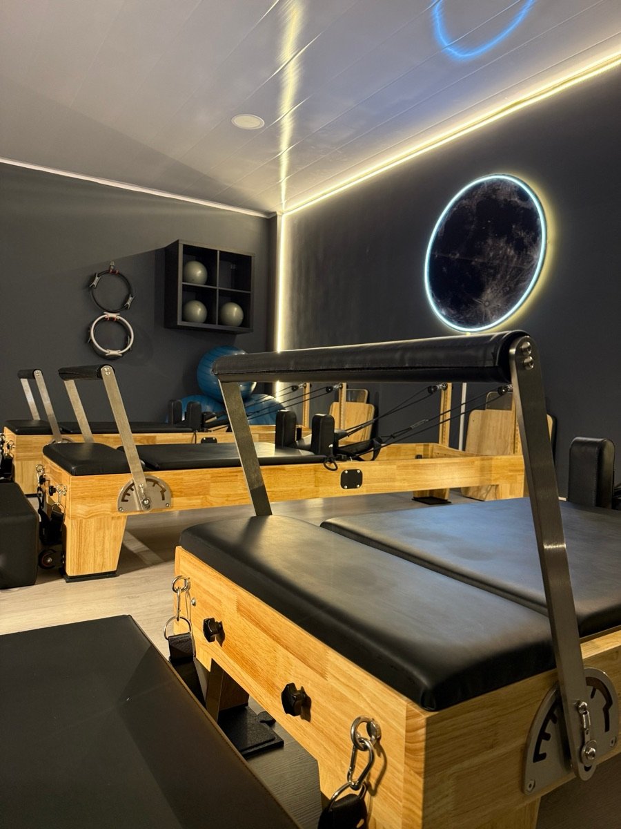 Reformers de madera bajo la luna del estudio de pilates en Cedritos